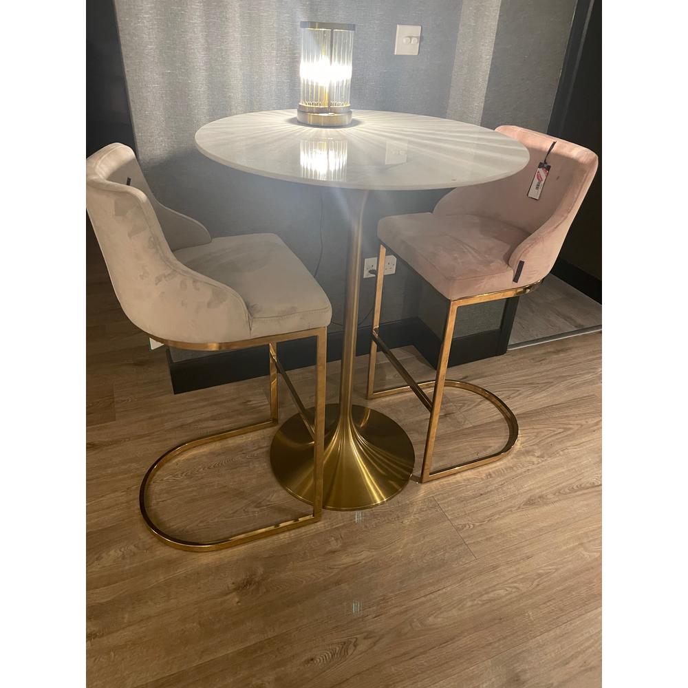Two Bolton K velvet counter bar stools with gold frames, one pink, one stone, beside a white marble bar table.