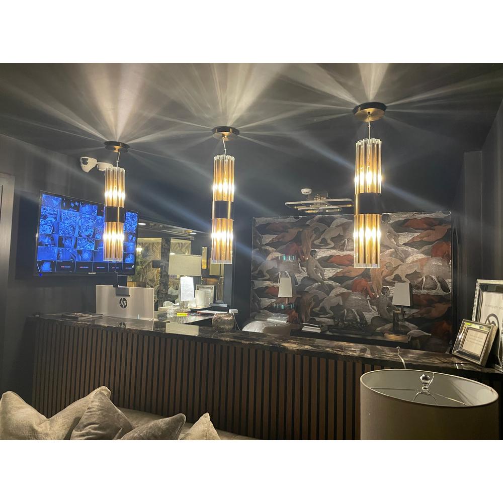 Three illuminated Colmar brushed brass pendant lights with clear glass shades in a modern room.