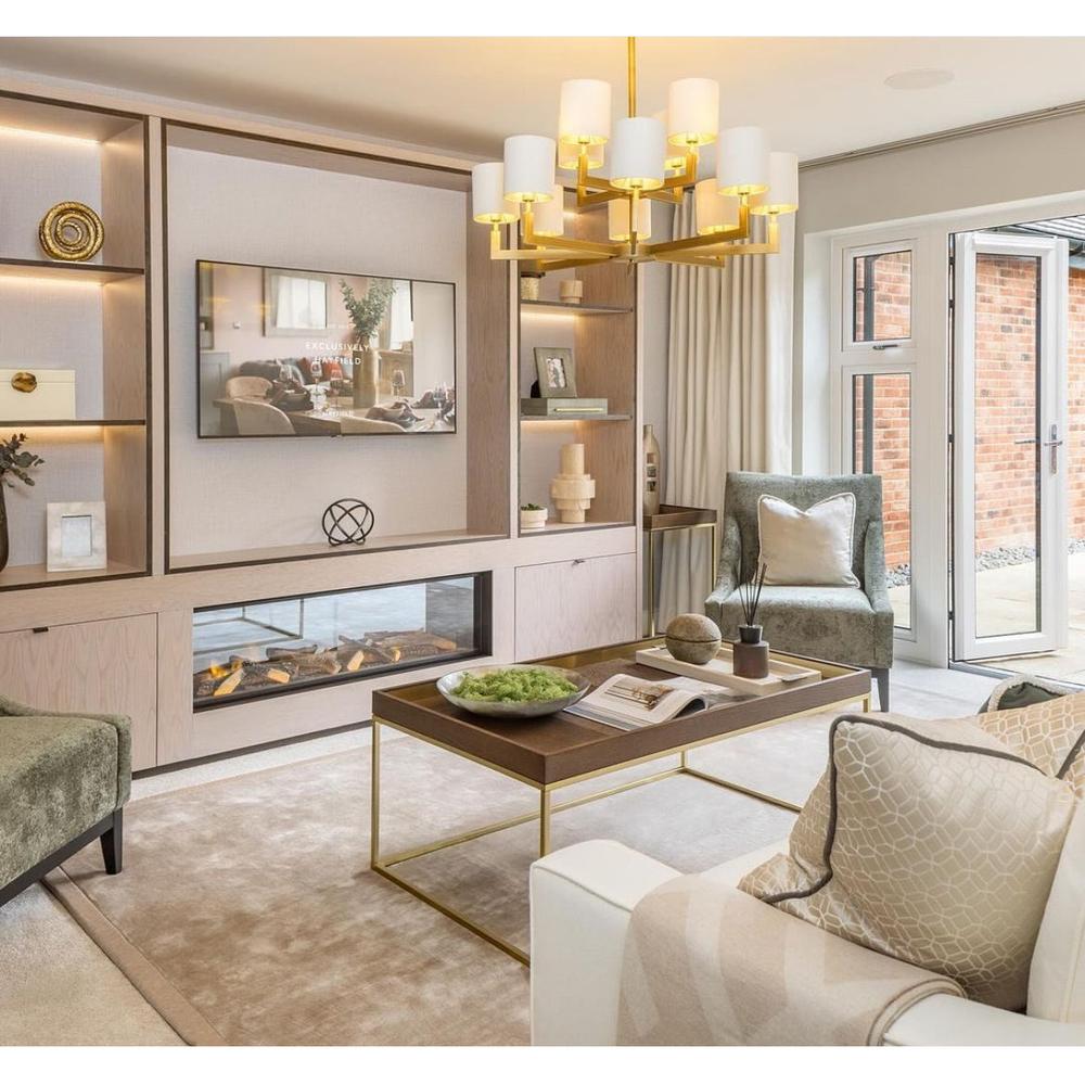Ealga Twelve Arm Chandelier in a brass finish with white shades, illuminating a modern living room.