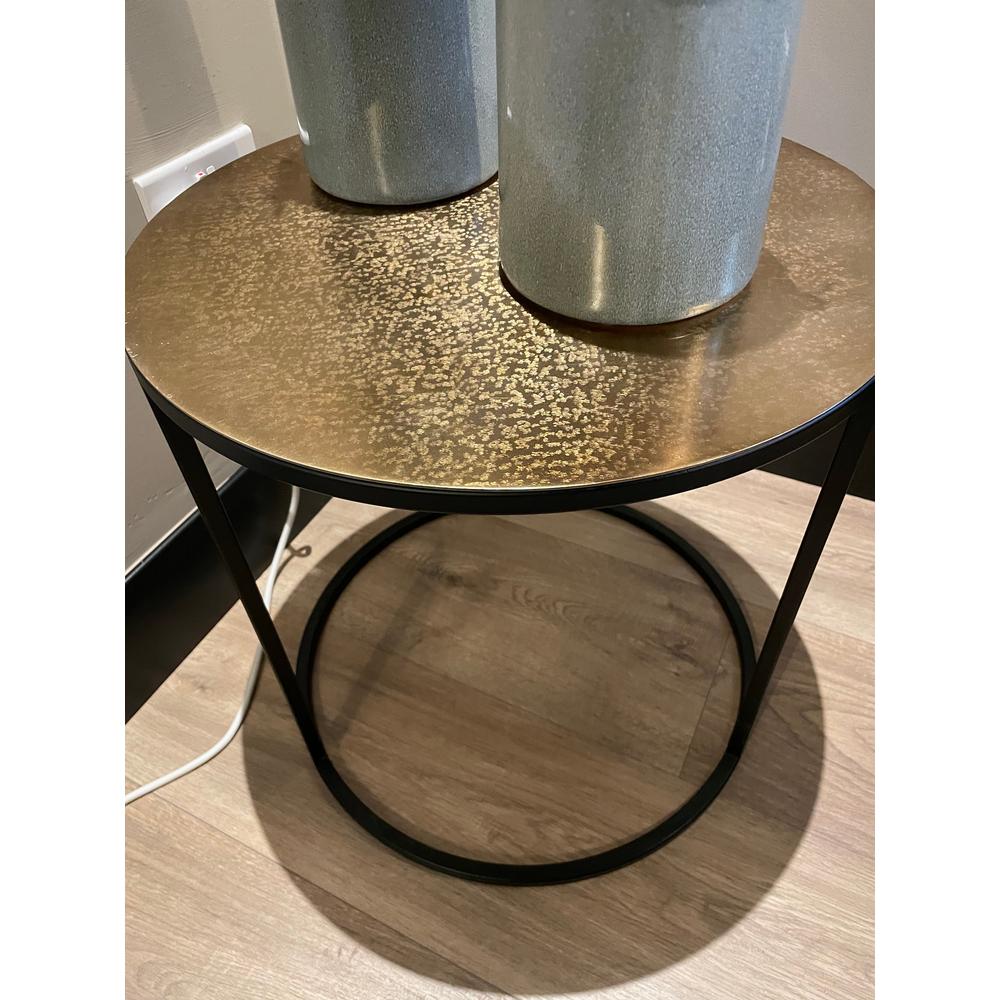 Logan corner table with a round gold-colored top and a black iron frame.