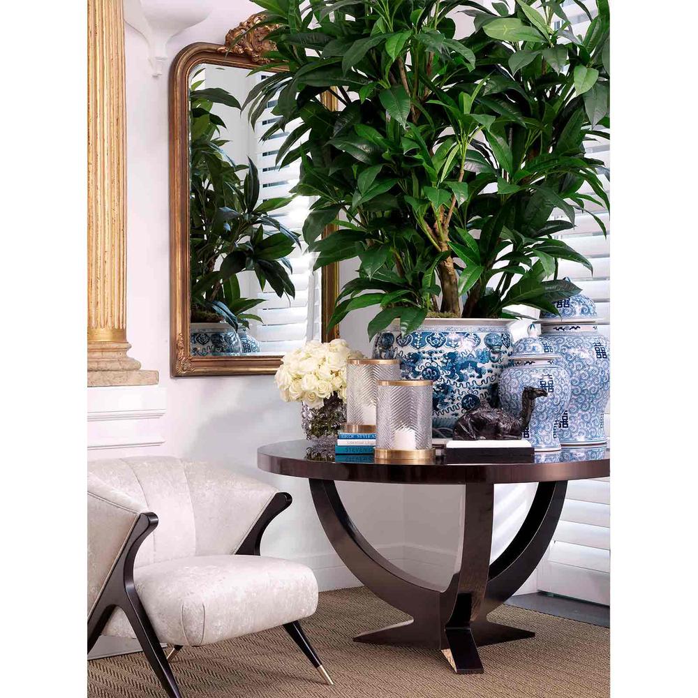 Pavone Occasional Armchair in off-white fabric with dark wood and brass legs, beside a round table with decor.