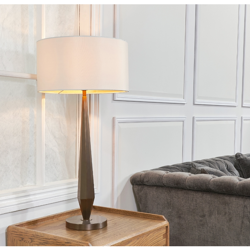 Aasone designer table lamp in dark brass with a cream shade, 77.5cm tall, on a wooden side table.