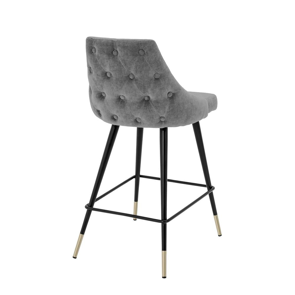 Grey velvet Cedro bar stool with tufted back, black tapered legs, and gold-capped feet.