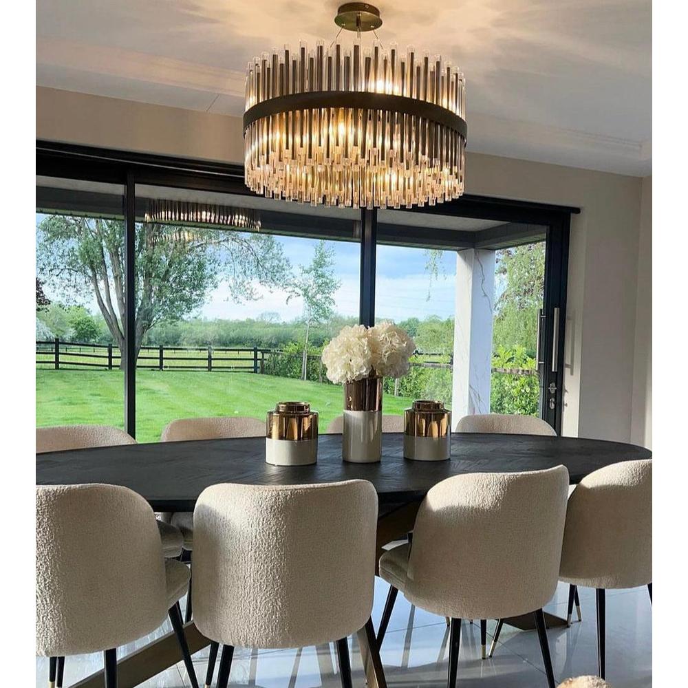 Colmar 80cm brushed brass chandelier with clear glass rods suspended over a black dining table.