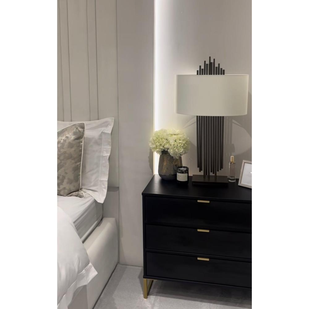 Vienna Bronze Table Lamp by RV Astley with a white shade and bronze metal base, on a black nightstand.